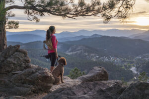 A hispanic woman hiking with her dog, at sunset, in the Rocky Mountains near Denver, Colorado