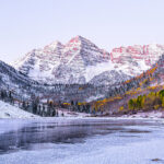 Maroon Bells morning sunrise panorama with sunlight on peak in Aspen, Colorado rocky mountain, autumn yellow foliage and winter snow